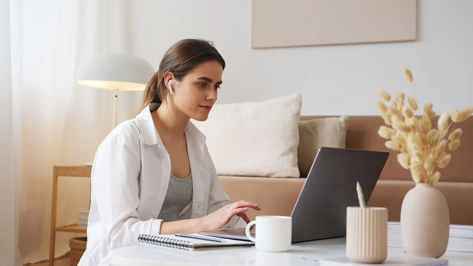Iemand werkt thuis aan een laptop met oortjes in
